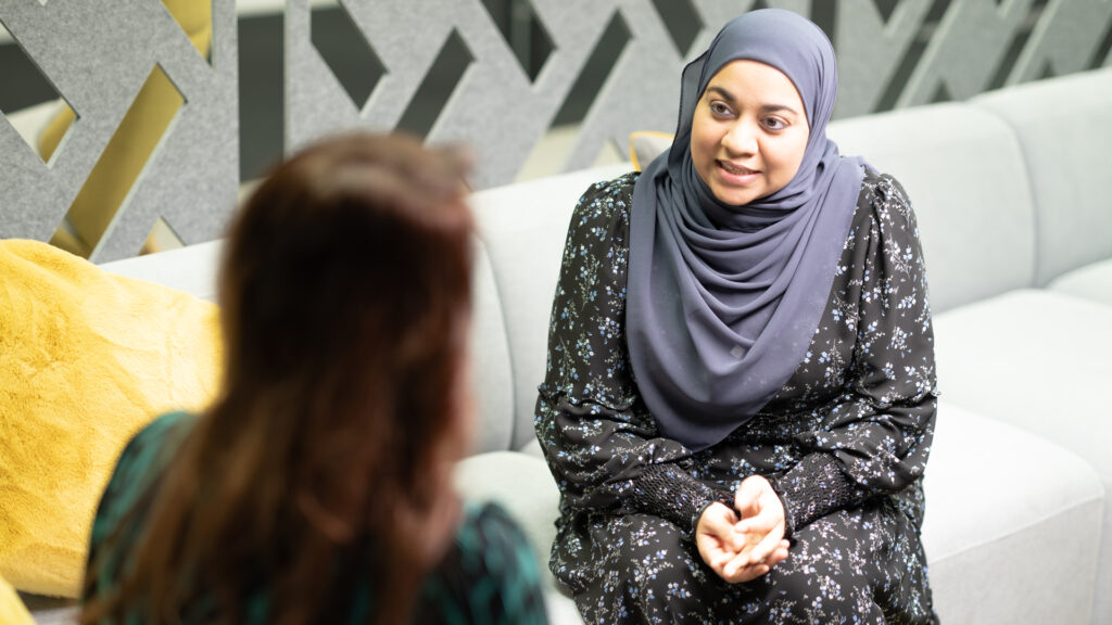 Two female colleagues sitting on a office sofa in discussion