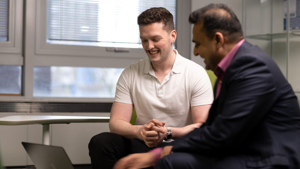 Two male colleagues in discussion looking at a laptop
