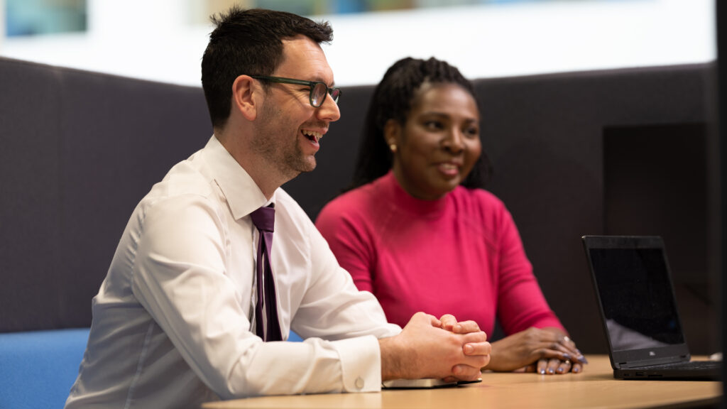Two members of staff seated around an office table