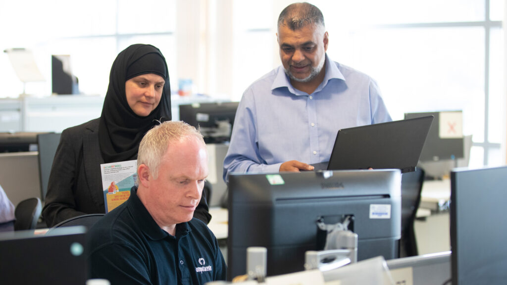 Three members of staff standing in the office around a desktop computer