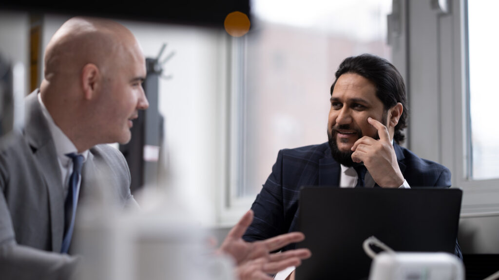two male members of staff in an office, with laptop